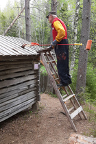 Puuladon kattoa tervaamassa Heikki Santaholma. Kuvan otti Pekka Tuomainen, joka oli toisena tervarina.